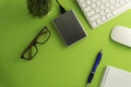 Top view of blank paper page on green background office desk and different objects. Minimal flat lay style Royalty Free Stock Photo