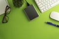 Top view of blank paper page on green background office desk and different objects. Minimal flat lay style