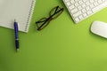 Top view of blank paper page on green background office desk and different objects. Minimal flat lay style