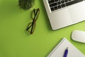 Top view of blank paper page on green background office desk and different objects.