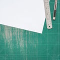 Top view of blank paper page A4 on old green cutting mat with stainless steel ruler, cutter knife, copy space for text, flat lay Royalty Free Stock Photo