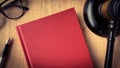 Top view of blank red cover book with gavel as background. Royalty Free Stock Photo