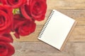 Top view of blank sheet of notebook and red rose on rustic brown wooden table.