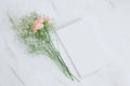 blank white notebook and boquet of carnation and gypsophila flowers on a marble background Royalty Free Stock Photo