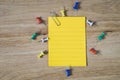 Blank yellow note paper with paper clip and thumbtacks on grunge brown wooden desk Royalty Free Stock Photo