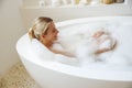 Top view on blonde young beautiful woman lying in bubbles foam in bath. Relaxation. Royalty Free Stock Photo