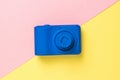 Top view of a blue camera on a yellow and pink background