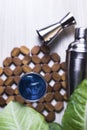 Top view. Blue cocktail in glass with ice and cocktail shaker and green leaves on wooden table. Summer refreshing cocktails drinks Royalty Free Stock Photo