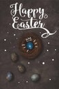 top view of blue easter egg with crown in nest on concrete table with Happy