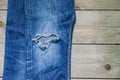 Top view of blue faded jeans with a hole on wooden background. Beauty, fashion and shopping concept. Copy space for text Royalty Free Stock Photo
