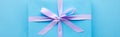 Top view of blue gift with violet ribbon on blue background, panoramic shot.