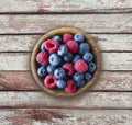 Top view. Blue and red berries in bowl. Ripe raspberries and blueberries on a wooden background. . Background of mix berries with Royalty Free Stock Photo