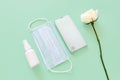 Top view of blue surgical protective mask, smartphone, liquid antimicrobial spray - mockup of unbranded white plastic spray bottle