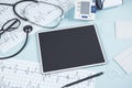 Top view of blue table with blank tablet, stethoscope, cardiogram, pen, other items and mock up place. Doctor`s office, workplace Royalty Free Stock Photo