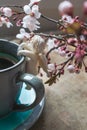 Top view of a blue vintage cup of coffee with an angel figurine and spring tree branches on wooden background Royalty Free Stock Photo