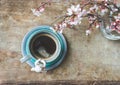 Top view of a blue vintage cup of coffee with an angel figurine and a vase with spring tree branches on wooden background Royalty Free Stock Photo