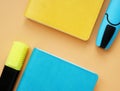 Top view of blue and yellow notepads and markers on an orange desk.