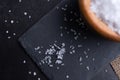 Top view of a blurred wooden bowl full of sea salt on a black stone board Royalty Free Stock Photo