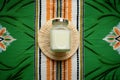 top view of body lotion in a green jar on a rattan mat