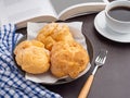 Top view of a book with choux cream on a plate and a white coffee cup on a table. Royalty Free Stock Photo