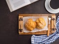 Top view of a book with choux cream on a wooden tray and a white coffee cup on a table. Royalty Free Stock Photo