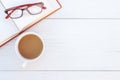 Top view book, glasses and coffee cup on white wooden table