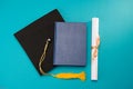 Top view of book, graduation mortarboard and diploma on blue Royalty Free Stock Photo