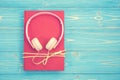 Book and new modern pink music headphone on blue wooden plank ba Royalty Free Stock Photo