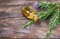 Top view Bottle glass of essential rosemary oil with rosemary branch and flower on wooden rustic background