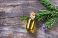 Top view Bottle glass of essential rosemary oil with rosemary branch and flower on wooden rustic background