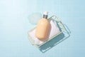 Top view of a bottle of shower gel placed on a rolled towel in an iron basket, next to a little white foam on a light blue Royalty Free Stock Photo