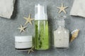 Top view of bottle of skin lotion, cream, sea salt, sea shell and stars on the grey stone surface