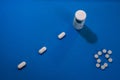 Top view of bottle and white tablets on blue background Royalty Free Stock Photo