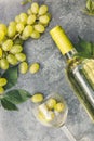 Top view of bottle white wine, green vine, wineglass and ripe grape on vintage gray stone table background. Wine shop Royalty Free Stock Photo