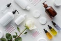 top view of bottles of cream cosmetic pads and rose on white surface