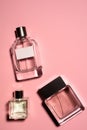 top view of bottles of various of perfumes on pink surface