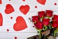 Top view bouquet of red roses and paper hearts on white wooden b