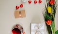 top view of a bouquet of tulips with heart shaped chocolate candies wrapped in red foil, glass of wine, small brown paper greeting Royalty Free Stock Photo