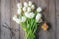 Top view, bouquet of white tulips, scissors and gift box on wooden background. Royalty Free Stock Photo