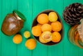 top view of bowl of apricots and jar of peach jam with compote and pinecone on green background Royalty Free Stock Photo