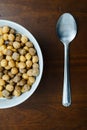 Top view of a bowl of cereals and a silver spoon on a wooden table