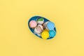 Top view of bowl with easter colorful eggshell in trendy blue, pink, golden, green colors on yellow backdrop. Flat lay