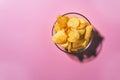 Top view of a bowl full of potato chips pink pastel background. space for text for space copy space