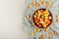 top view of bowl full of yellow and red cherries on plaid cloth on right side and white background with copy space Royalty Free Stock Photo