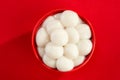 Top view of a bowl of glutinous rice balls against a red background