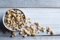 Top view of bowl with a handful of cashew nuts on wooden background