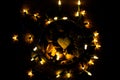 Top view of a bowl of heart-shaped cookies surrounded by decorative lights in the dark