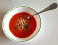 Top view of bowl of homemade tomato soup topped with shredded cheese and freshly snipped herbs