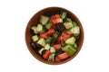 Top view on a bowl of homemade vegetable salad with tomatoes, cucumbers and black olives, isolated on white background Royalty Free Stock Photo