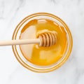 Top view of a bowl with honey in which lies a spoon for honey. Square photo. Marble background.